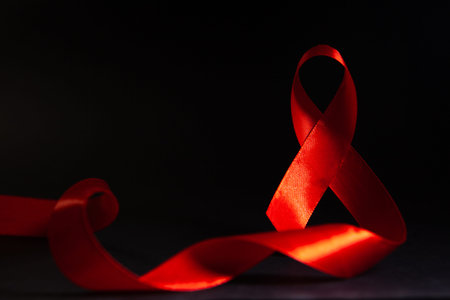 Red ribbon on black background. Symbol of World Aids Day.
