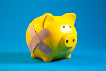 Piggy bank with adhesive bandage on blue background. Health care and medical concept.の写真素材