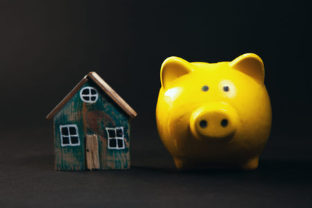 Piggy bank and house on black background. Saving money conceptの写真素材