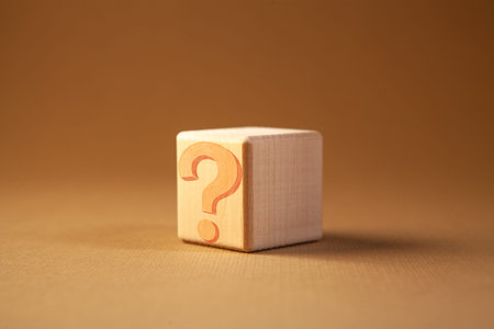 Wooden cube with a question mark on a brown background. Business concept