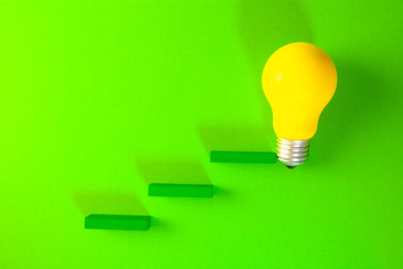 Yellow light bulb and green stairs on a green background with copy space