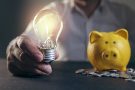 Man hand holding a light bulb and saving money with piggy bank