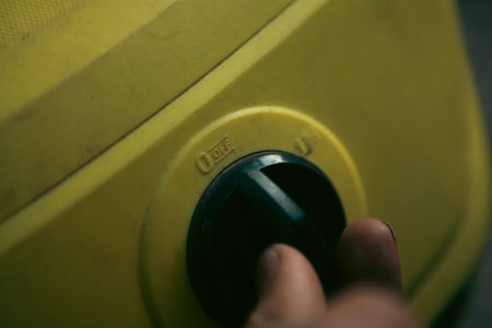 Close-up of a hand pressing a button on a yellow vacuum cleaner