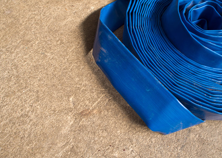 Blue canvas hose rolled on the concrete floorの写真素材