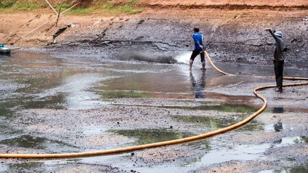 CHACHOENGSAO THAILAND - JULY 13 : Unidentified men control high pressure water jet nozzle to clean the mud at the bottom of the pond on July 13, 2016 to prepare the pond clean, for next time shrimp farming, Chachoengsao, Thailand.のeditorial素材