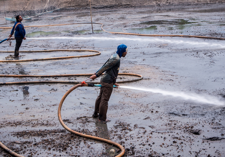 CHACHOENGSAO THAILAND - JULY 13 : Unidentified men control high pressure water jet nozzle to clean the mud at the bottom of the pond on July 13, 2016 to prepare the pond clean, for next time shrimp farming, Chachoengsao, Thailand.のeditorial素材