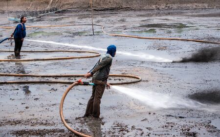CHACHOENGSAO THAILAND - JULY 13 : Unidentified men control high pressure water jet nozzle to clean the mud at the bottom of the pond on July 13, 2016 to prepare the pond clean, for next time shrimp farming, Chachoengsao, Thailand.のeditorial素材