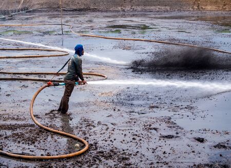 CHACHOENGSAO THAILAND - JULY 13 : Unidentified men control high pressure water jet nozzle to clean the mud at the bottom of the pond on July 13, 2016 to prepare the pond clean, for next time shrimp farming, Chachoengsao, Thailand.のeditorial素材