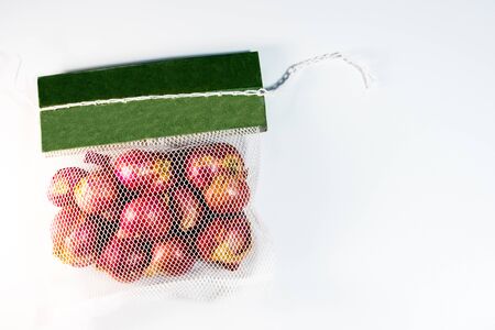 Red onions in mesh bag and some on floor isolated on white backgroundの写真素材