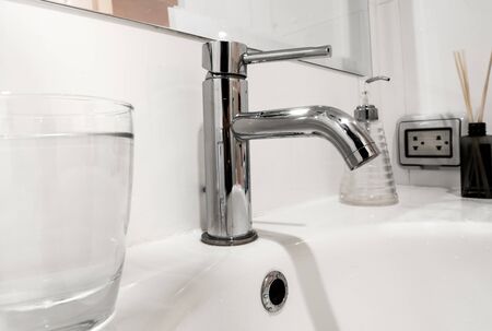 White bathroom faucet and wash basin with water glass