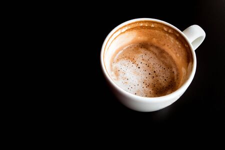 Stain of Hot milk coffee and soft froth inside the white ceramic cup, Half a cup of coffee