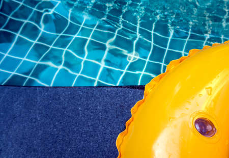 Bright yellow of the swimming tube is placed beside the poolの写真素材