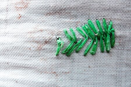 Rag green plastic rope sewing at the tear of old woven plastic bag