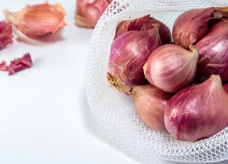 Red onions in mesh bag and some on floor isolated on white backgroundの写真素材