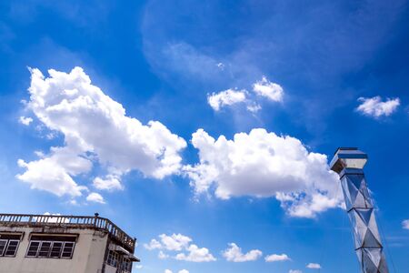 Shiny steel smokestack and cloud in blue skyの写真素材