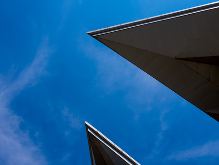 Triangle shapes of roof of the modren building and bright blue skyの写真素材