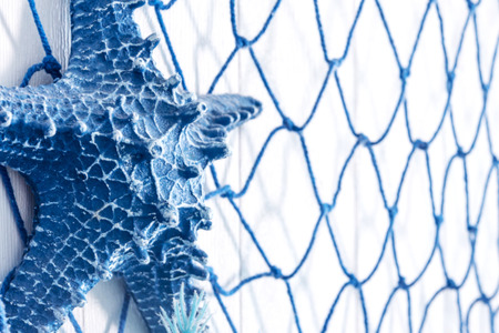 Blue net and artificial starfish made of plastic decorate in the beach and sea theme on wallの写真素材