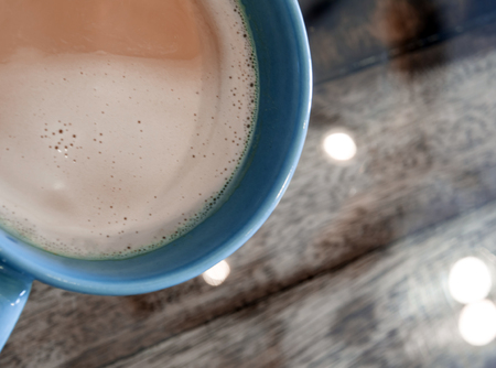 Milk coffee in a blue cup on the wooden and top glass tableの写真素材