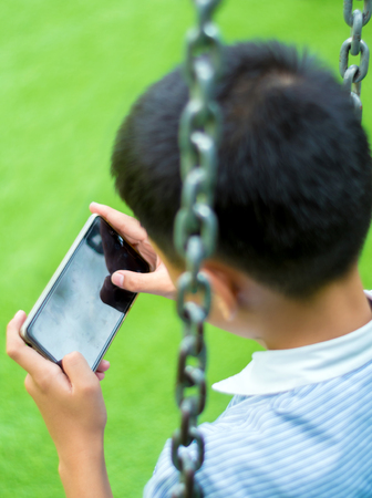 Serious boy playing on smartphone, Children playing game on smartphoneの写真素材