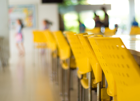 Empty tables and old yellow chairs that nobody sit in the cafeteriaの写真素材