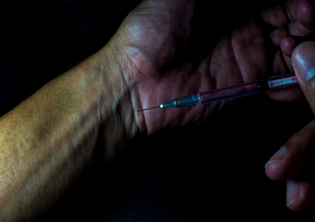 Man injecting with syringe to his handの写真素材