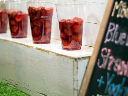 Strawberry and syrup in the plastic glass show on wooden shelf prepare for made to smoothies by the customer orderの写真素材
