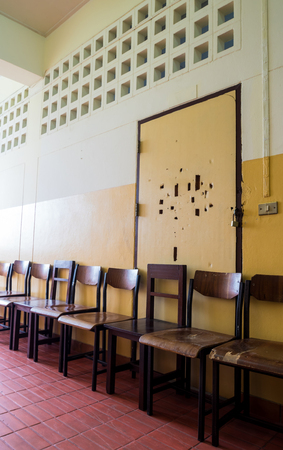 Unused student chair store in front of the broken door of an old classroomの写真素材