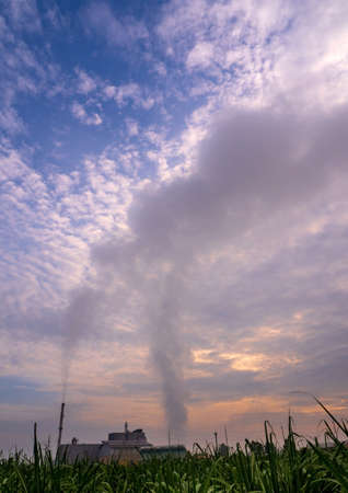 Smoke from the boiler and the steam from the cooling tower in the power plant. It is located in the middle of an agricultural areaの写真素材