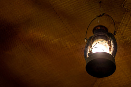 Bright light in an ancient lantern hanging in an old roomの写真素材