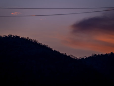 Silhouette of mountain with magenta sky and clouds at duskの写真素材