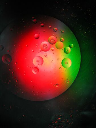 floating drop oil on the water with difference colour light, moving around look like a plant in spaceの写真素材