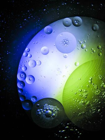 floating drop oil on the water with difference colour light, moving around look like a plant in spaceの写真素材