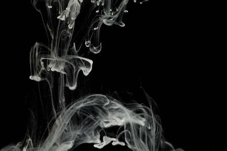 selective focus white liquid drop in clear water with lighting, look like smoke in the night.の写真素材