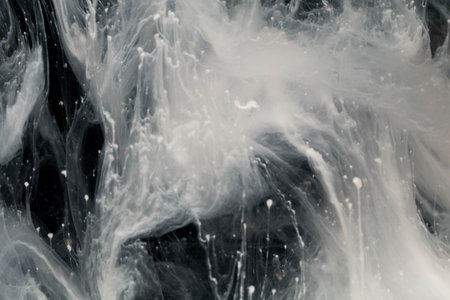 close up of white acrylic paint splash in water on black background.の写真素材