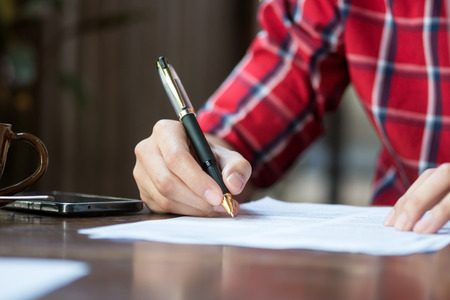 A man is writing on a paper.の写真素材