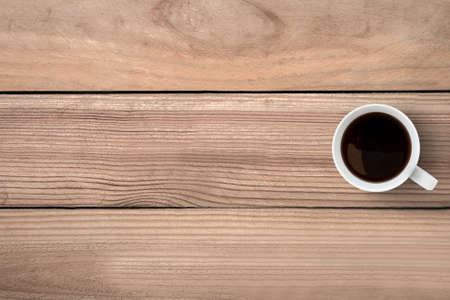 A cup of coffee is on top of wood table. Top view with copy space, flat lay.