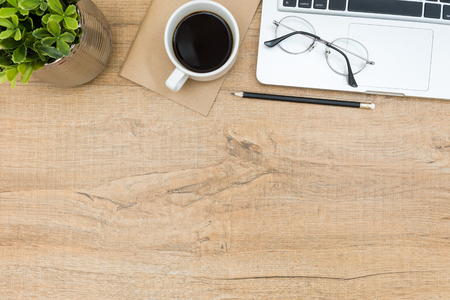 Wood desk table with laptop, coffee, and supplies. Top view with copy space, flat lay.の写真素材