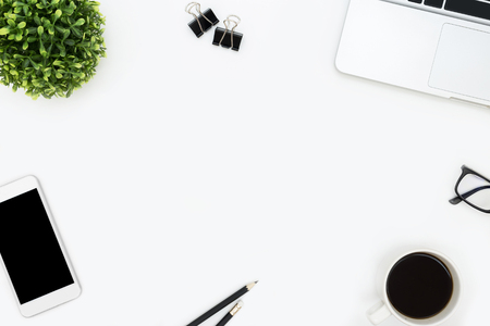 White office desk table with laptop, smartphone, coffee and supplies. Top view with copy space, flat lay.