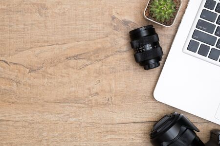 Wood photographer desk table with camera, lens and laptop. Top view with copy space, flat lay.の写真素材