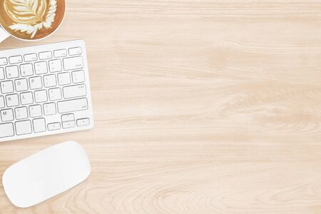 Minimal wood office desk table with computer mouse, keyboard and cup of coffee. Top view with copy...
