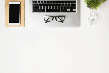 White office desk table with laptop computer, smartphone and supplies. Top view with copy space, flat lay.の写真素材