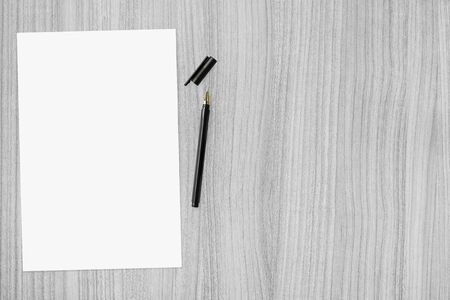 Blank a4 paper with pen are on top of wood table. Top view with copy space, flat lay.