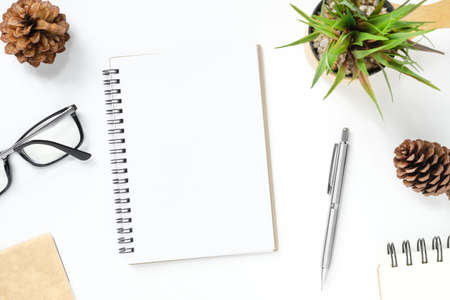 Blank notebook is on top of white office desk table with supplies. Top view, flat lay.の写真素材