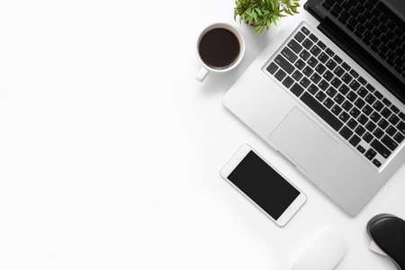 White office desk table with smartphone, laptop computer, cup of coffee and supplies. Top view with copy space, flat lay.の写真素材