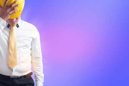 businessman holding hard hat on abstract purple background, copy space