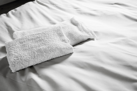 White hotel towels on white bed. Black and white picture.の写真素材