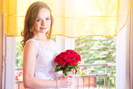 Young beautiful bride in wedding dress with red rose bouquet. Marriage and wedding concept image.の写真素材