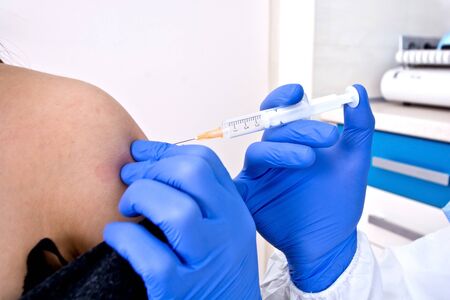 Doctor in protective suit uniform giving a vaccine to patient. Coronavirus outbreak. Covid-19 concept.の写真素材