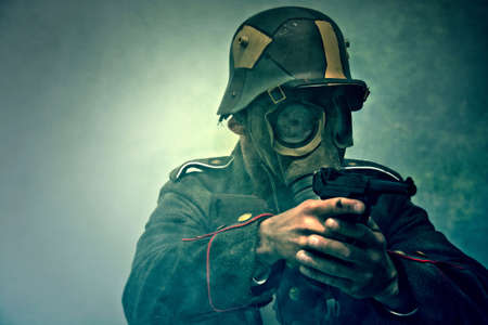 World War 2 Soldier in a gas mask aims his gun. War concept.の写真素材