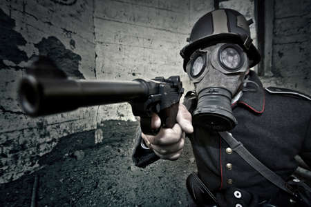 World War 2 Soldier in a gas mask aims his gun. War concept.の写真素材